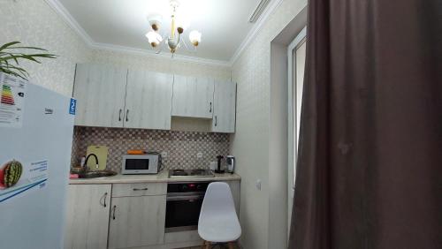 a kitchen with white cabinets and a white refrigerator at Ботанический сад Астана in Taldykolʼ