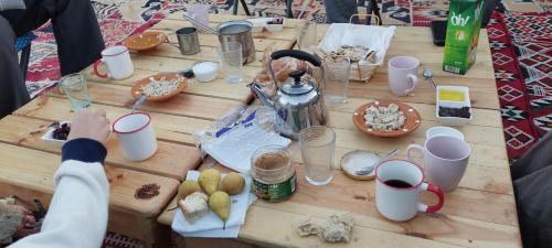 uma mesa de madeira com comida e bebidas em Private Camp25km-from DOUZ em Douz