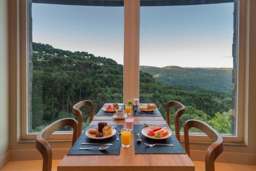 un tavolo in legno con piatti di cibo sopra davanti a una finestra di Laghetto Resort Golden Oficial a Gramado