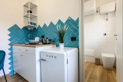 - un réfrigérateur blanc dans une cuisine avec du carrelage bleu dans l'établissement Sea City In Bed, à Naples