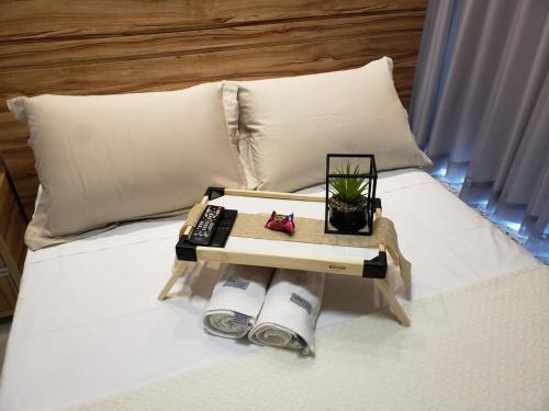 a bed with a tray with a remote control on it at 01 Qt.| 2 Hosp. | Linda Vista | Goiânia Shopping in Goiânia