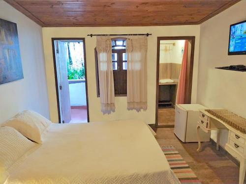 a bedroom with a bed and a desk and a window at Pousada Kokopelli in Lavras Novas