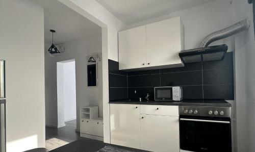 eine Küche mit weißen Schränken und einer Mikrowelle in der Unterkunft Park View Studio - NETFLIX in Bukarest