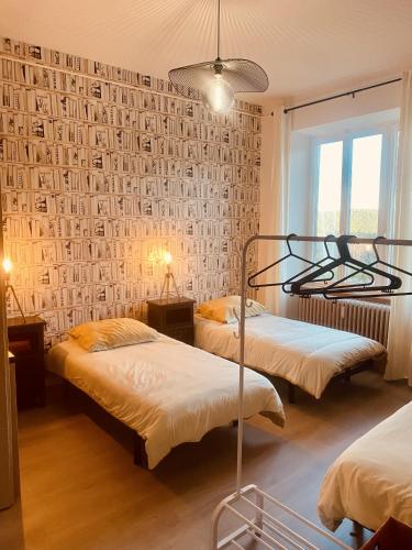 a bedroom with two beds and a wall with photographs at LA MARIEFACTURE - Comme un Livre Ouvert in La Petite-Pierre