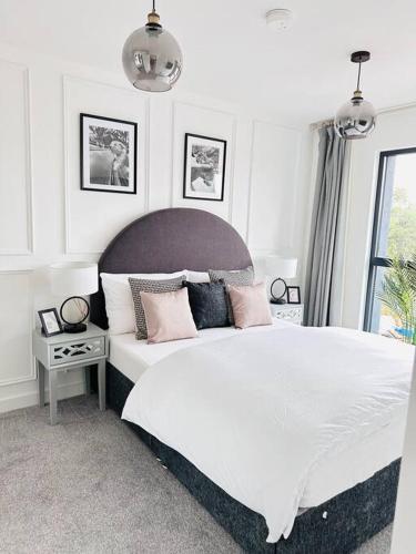 1 dormitorio con 1 cama blanca grande con almohadas rosas en Central Derby Urban 2 Bedroom Flat - An Oasis of Elegance! Free Parking and Wifi suitable for families and professionals en Derby