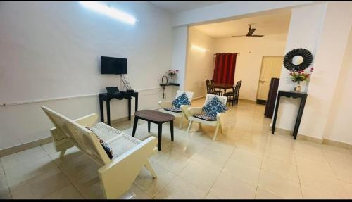 ein Wohnzimmer mit Sofas und Stühlen sowie einem TV in der Unterkunft Goa Suites Holiday Home in Calangute