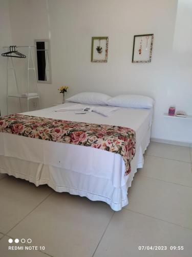 a bed in a white room with a white floor at Pousada Flor do Campo in Icapuí