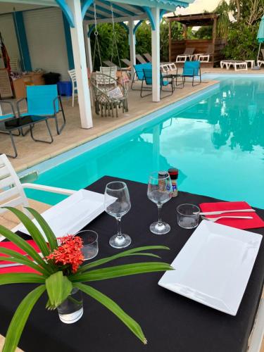 a table with wine glasses and flowers next to a swimming pool at Gîte Ty Koko in Saint-François
