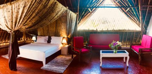 a bedroom with a bed and two chairs and a table at Villas Dora and Holly in Diani Beach