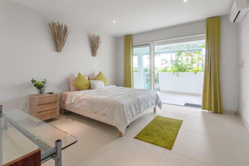 a white bedroom with a bed and a glass table at Maho Oceanfront Luxe: Modern and Spacious Condo in Maho Reef
