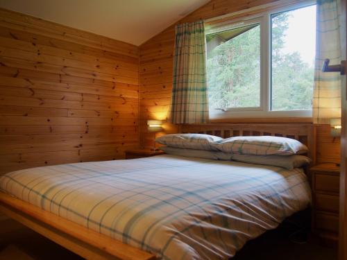 a bedroom with a bed and a window at Reuben's Highland Retreat - Speyside in Carrbridge