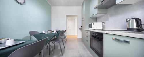 una cucina con banconi e sedie verdi e bianche di b&b Amaca a Pavia