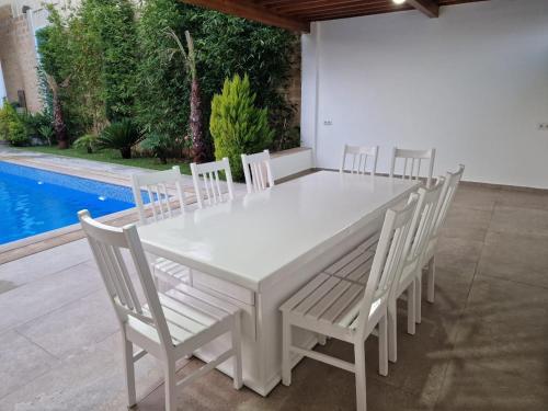 a white dining room table and chairs with a pool at Villa Fares Assilah 1 in Asilah