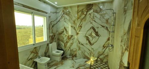 a marble bathroom with a toilet and a sink at Villa Fares Assilah 1 in Asilah