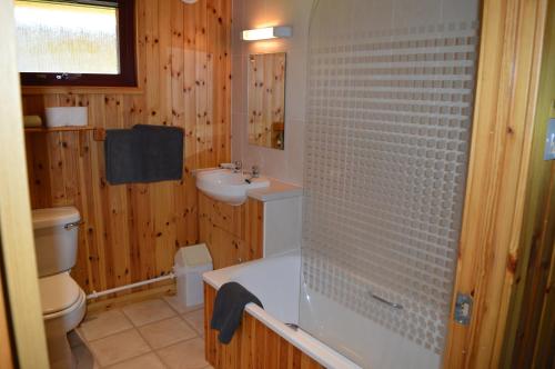 a bathroom with a tub and a sink and a toilet at Reuben's Highland Retreat - Speyside in Carrbridge