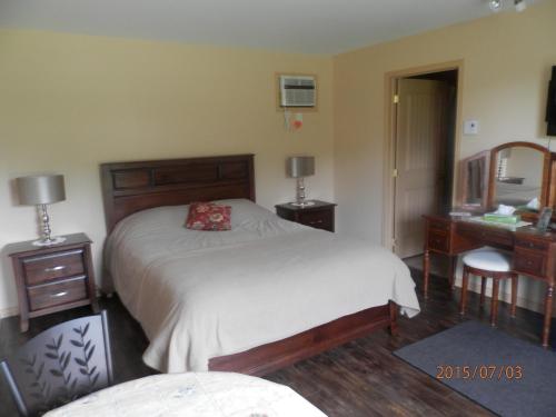a bedroom with a bed and a desk and a mirror at Motel la Maison de Travers in Baie-Sainte-Catherine