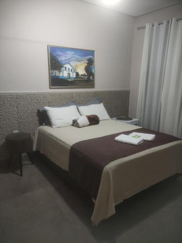 um quarto com uma cama e um quadro na parede em Pousada da Gi Suítes e Turismo em Chapada dos Guimarães