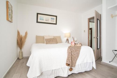 a white bedroom with a bed and a table at Casa Loba Suite 1 with an outdoor tub in Rincon