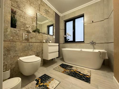a bathroom with a tub and a toilet and a sink at La Stejari Deluxe Apartment in Suceava