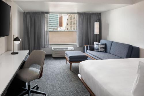 a hotel room with a bed and a couch at Courtyard by Marriott Stamford Downtown in Stamford