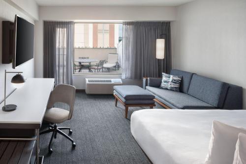 a hotel room with a bed and a couch at Courtyard by Marriott Stamford Downtown in Stamford
