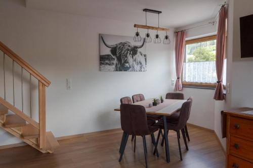 a dining room with a table and a bull picture on the wall at Ferienwohnung am Bauernhof, Korbingerhof in Rinn