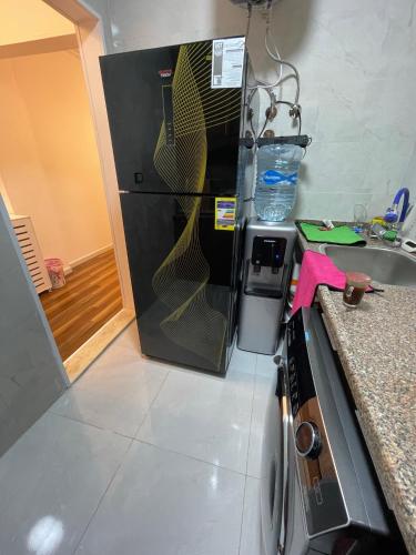 a kitchen with a black refrigerator with goldplates on it at luxury apartment at Obour, 5th floor no elevator in Cairo