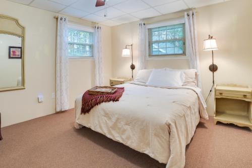 a white bedroom with a bed and two windows at Roscommon Cottage - Walk to Higgins Lake! in Roscommon