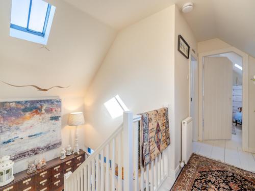 una escalera en una casa con paredes y techos blancos en The Old Net Shed, en Whitehills