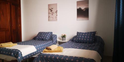 two beds in a room with blue and white sheets at Sunhouse in Playa Honda