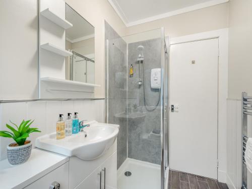 a white bathroom with a shower and a sink at Argyle House in Rothesay