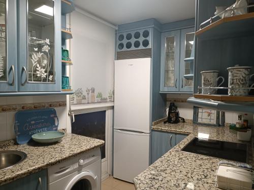 a kitchen with blue cabinets and a white refrigerator at Encanto de Granada - Parking gratuito in Armilla