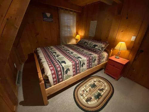 a bedroom with a bed and a table with a lamp at U.P Norse A-frame close to Powderhorn Ski Resort in Ironwood