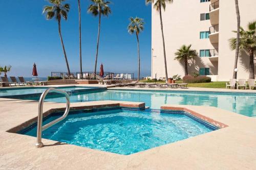 a swimming pool with palm trees and a building at Oceana Casa Del Mar in Rosarito