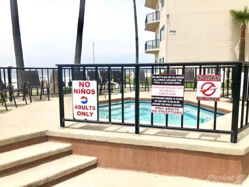 a fence with signs in front of a swimming pool at Oceana Casa Del Mar in Rosarito