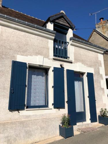 a house with blue shutters and a window at La cav ô lauriers in Lunay