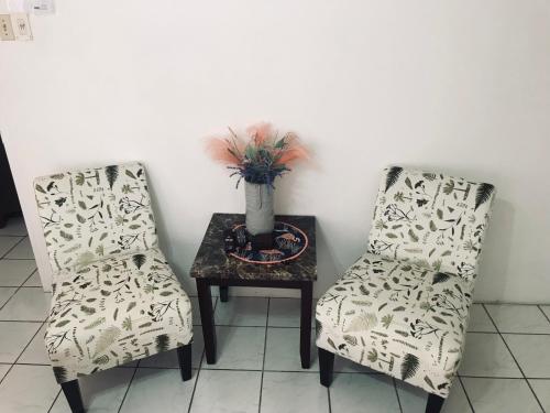 two chairs and a table with a vase on it at HCEAS villa is 5 min fr. airport & to the beaches in Bon Accord