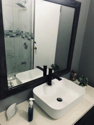 a bathroom with a white sink and a mirror at HCEAS villa is 5 min fr. airport & to the beaches in Bon Accord