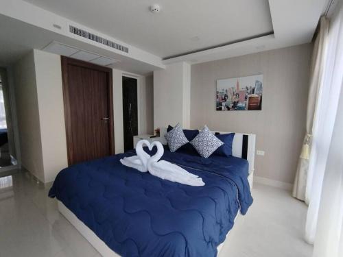 a bedroom with a blue bed with a towel on it at Grand Avenue Pattaya in Pattaya Central