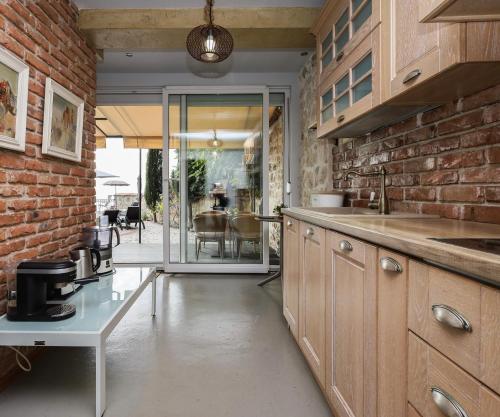 a kitchen with wooden cabinets and a brick wall at Villa Alenor Nessebar in Nesebar