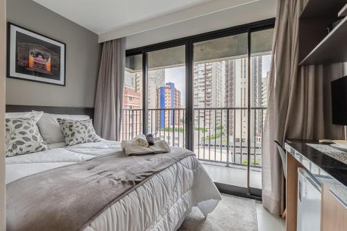 een slaapkamer met een bed en een groot raam bij Studios modernos e lindos na região da Bela Vista in Sao Paulo