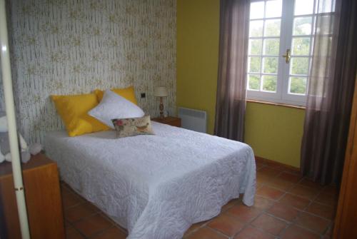 - une chambre avec un lit blanc aux murs jaunes et une fenêtre dans l'établissement Les lantanas, à Bandol