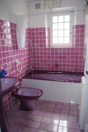 une salle de bains carrelée de rose avec des toilettes et une fenêtre. dans l'établissement Les lantanas, à Bandol