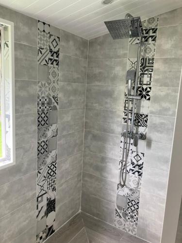 a shower with black and white tiles on the wall at Gîte Ty Koko in Saint-François
