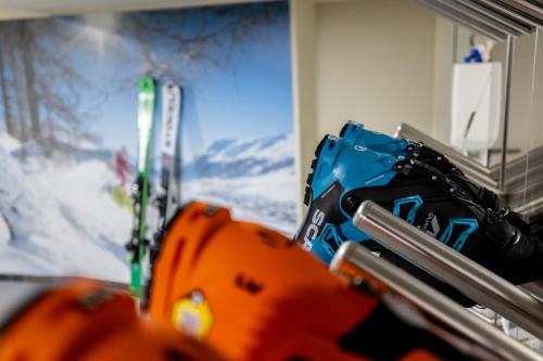 een groep ski's en handschoenen naast een schilderij bij Camana Veglia in Livigno