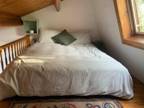 a bedroom with a bed with white sheets and a window at The Studio in Beeston