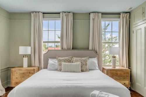 a bedroom with a large bed with two windows at The Palmetto House B- Walk To King Street in Charleston
