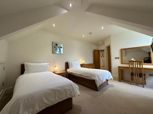 a bedroom with two beds and a mirror at Meadows Barn in Chelmsford