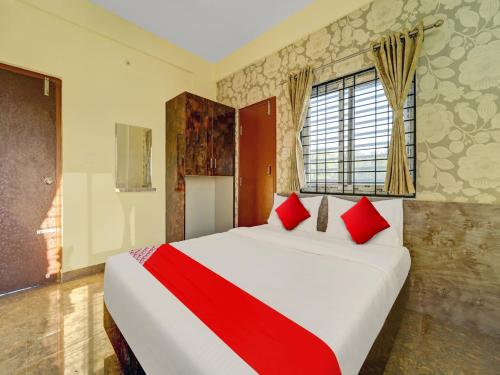 a bedroom with a large bed with red pillows at OYO Flagship Mathrushree Lodge in Yelahanka