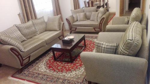 een woonkamer met banken en stoelen en een tafel bij Cozy fully well furnished apartment for rent in Mesaha Square - Dooki in Caïro